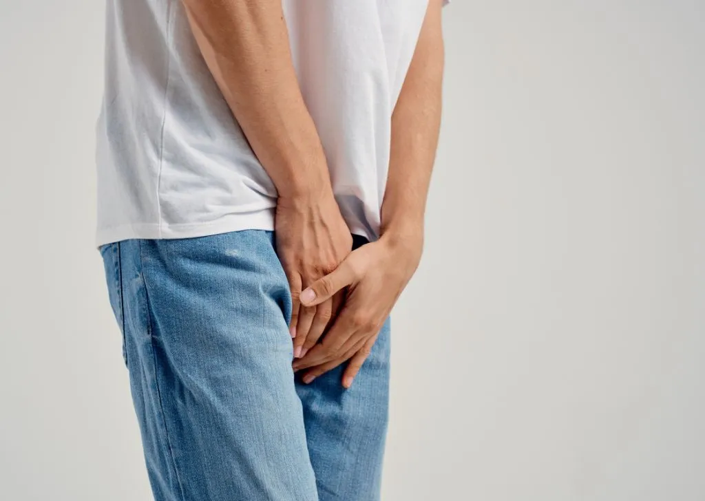 A man applying pressure to his groin to temporary sooth the pain caused by frenulum tear.
