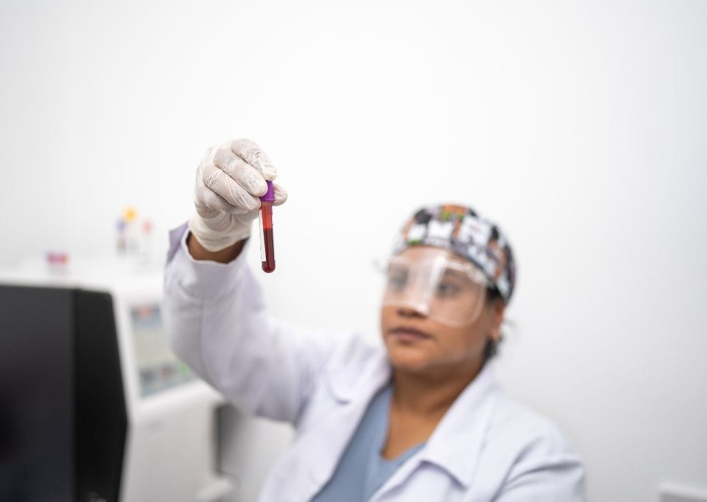 A doctor examining a vial of blood sample before processing it for P Shot treatment. 