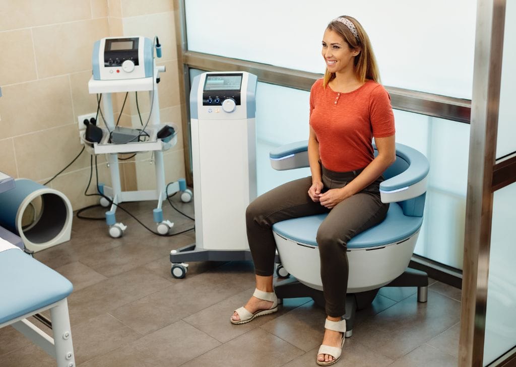 A woman sitting on a kegel exercise machine learning how to do kegel exercises. 